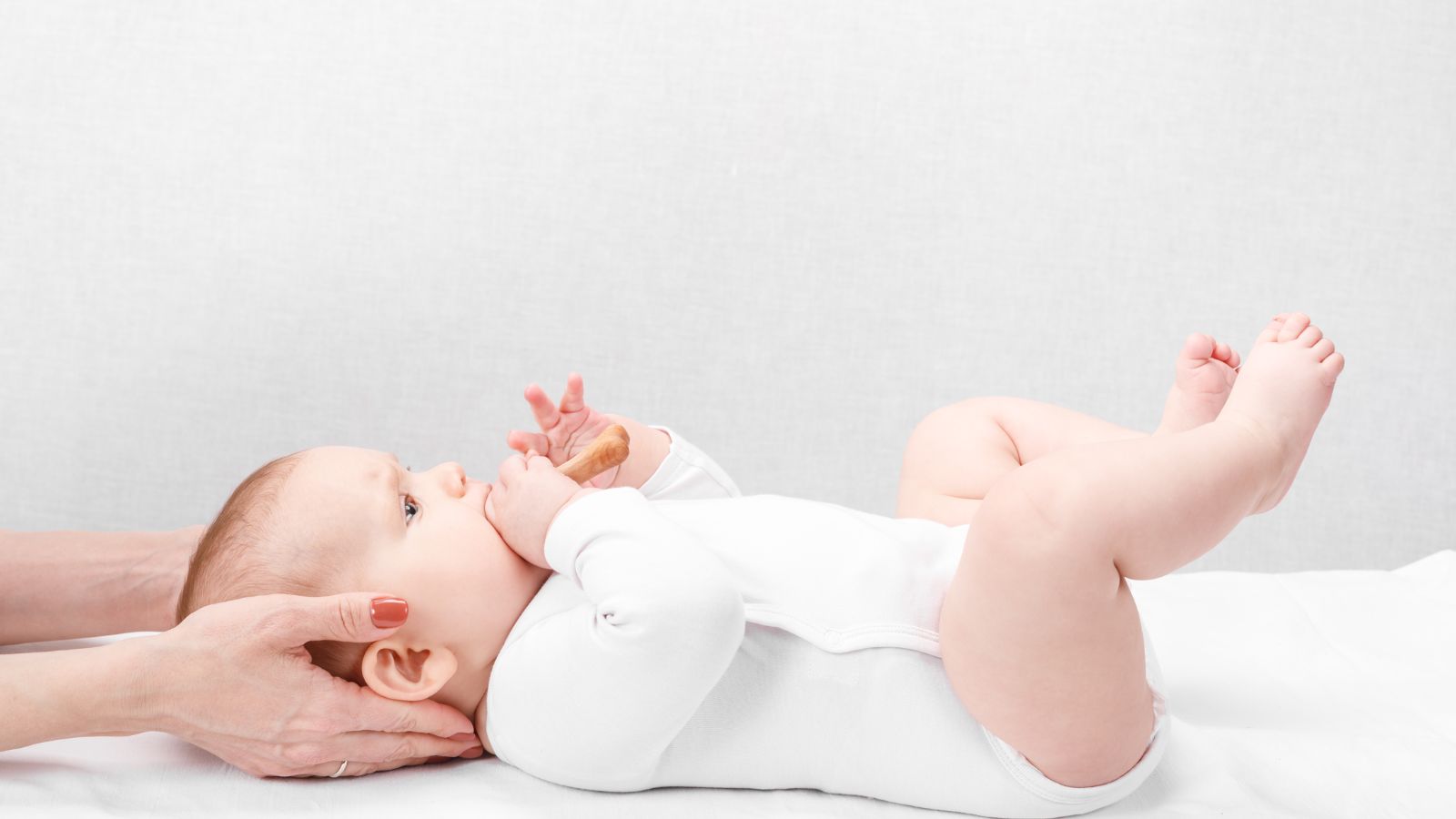 Osteópata pediátrica tratando a un bebé tumbado boca arriba
