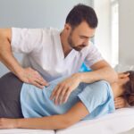 Fisioterapeuta aplicando terapia manual en la espalda de una paciente tumbada en camilla