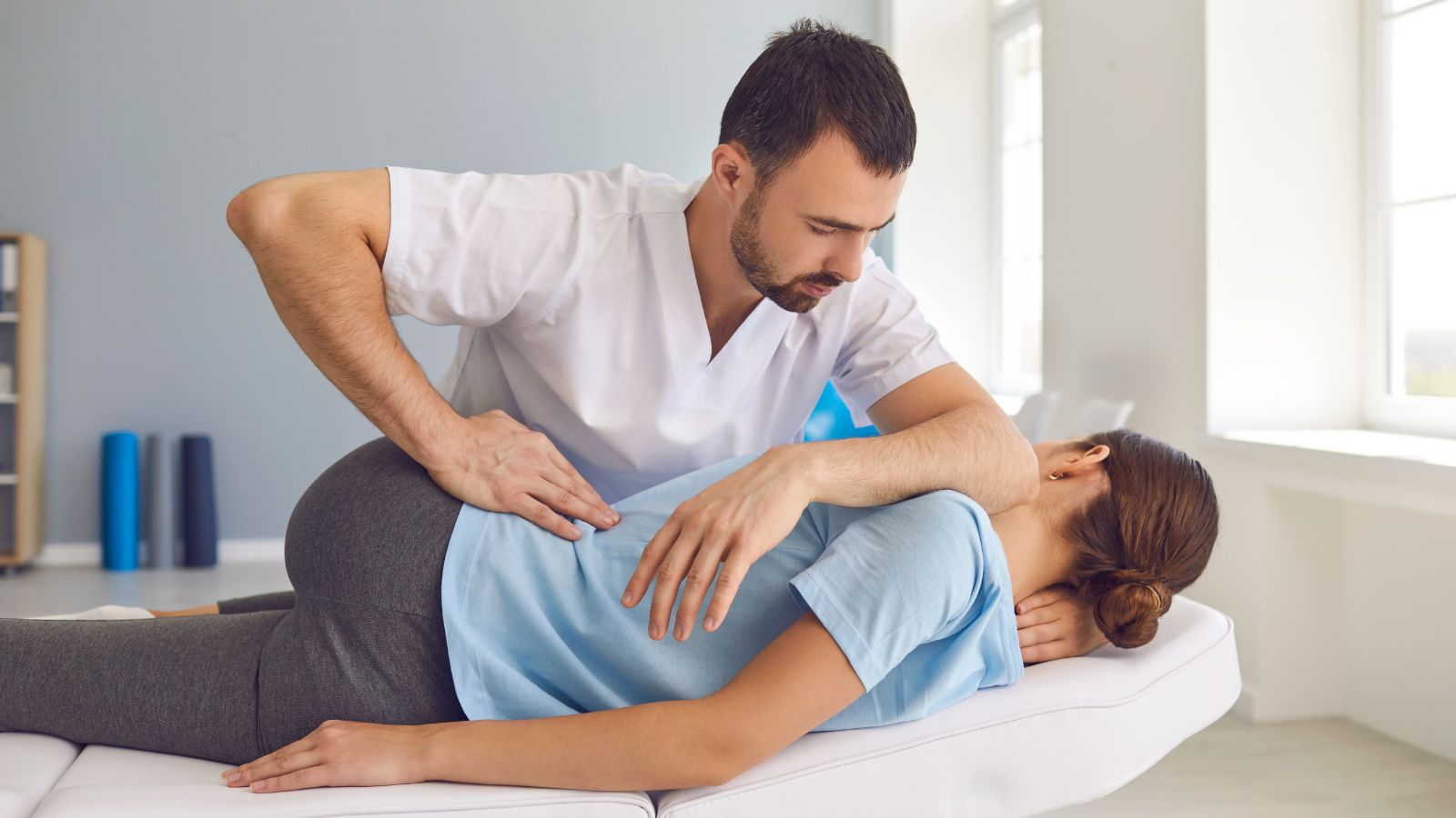 Fisioterapeuta aplicando terapia manual en la espalda de una paciente tumbada en camilla
