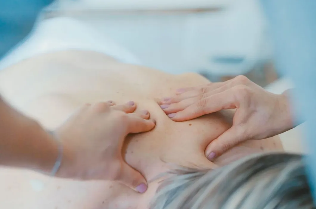 Manos de un terapeuta realizando terapia manual en la espalda de una paciente