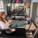 Paciente ejercitándose en una máquina reformer durante una clase de pilates en The Kine Hub