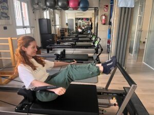 Paciente ejercitándose en una máquina reformer durante una clase de pilates en The Kine Hub