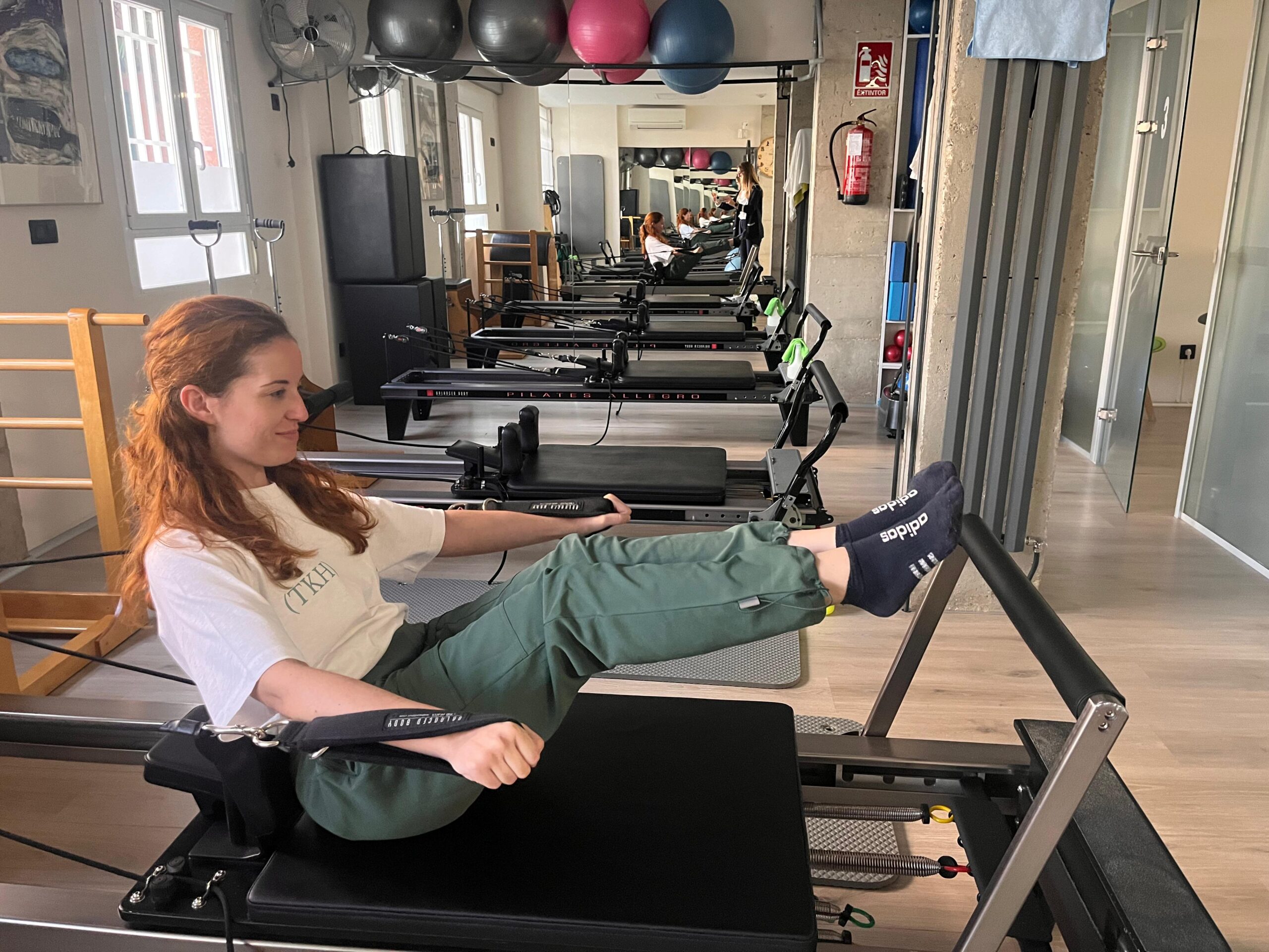 Paciente ejercitándose en una máquina reformer durante una clase de pilates en The Kine Hub