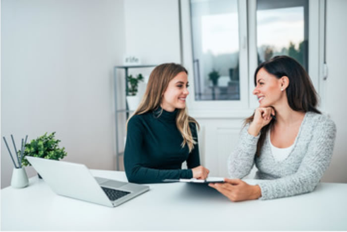 Dos mujeres conversando en una sesión de coaching frente a un portátil
